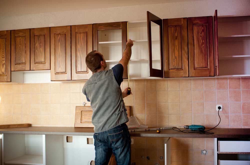 person measuring cabinets